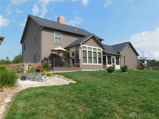 rear view of property with a wooden deck and a lawn