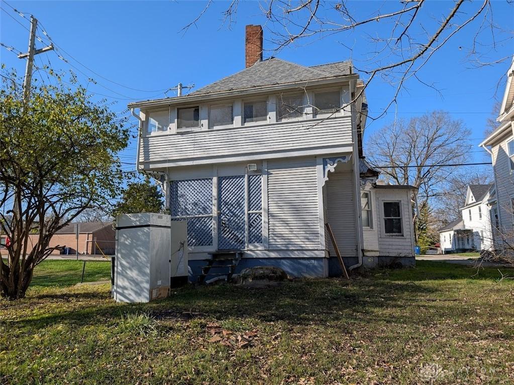 136 N Spring St, Wilmington, OH 45177 - rear view of property with a chimney, a lawn, and entry steps
