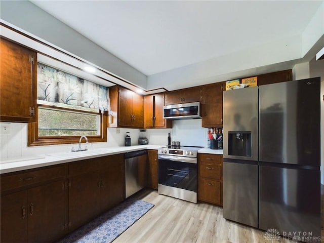 kitchen with sink, light wood-type flooring, stainless steel appliances, and dark brown cabinetry