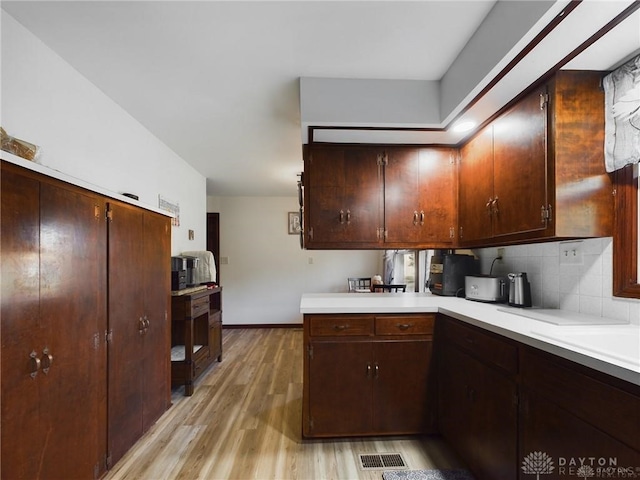 kitchen with backsplash, light hardwood / wood-style floors, and dark brown cabinetry