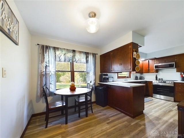 kitchen with light hardwood / wood-style floors, kitchen peninsula, sink, and appliances with stainless steel finishes