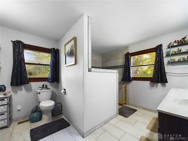 bathroom featuring plenty of natural light, toilet, walk in shower, and vanity