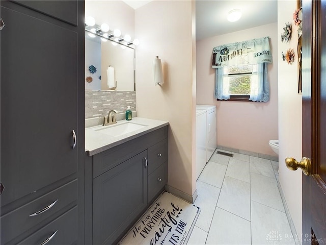 bathroom featuring separate washer and dryer, tile patterned flooring, backsplash, toilet, and vanity