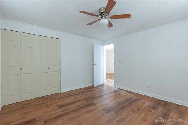 unfurnished bedroom with crown molding, ceiling fan, a closet, and dark wood-type flooring