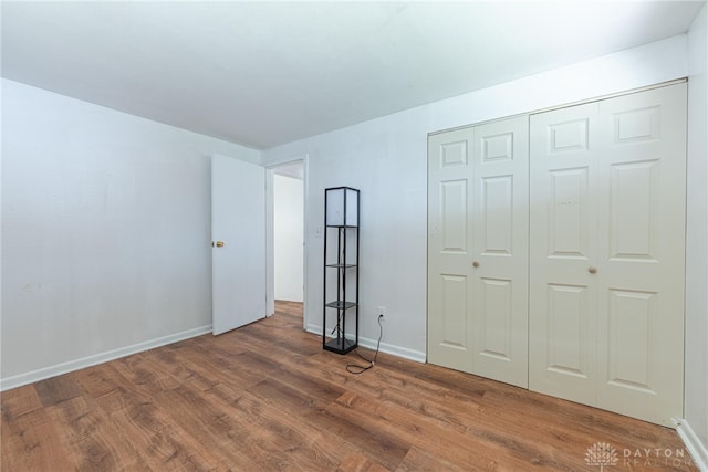 unfurnished bedroom featuring wood-type flooring and a closet