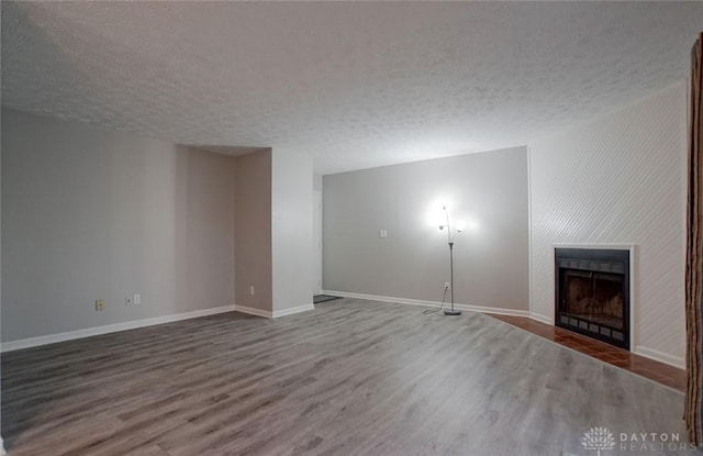 unfurnished living room with hardwood / wood-style flooring, a large fireplace, and a textured ceiling