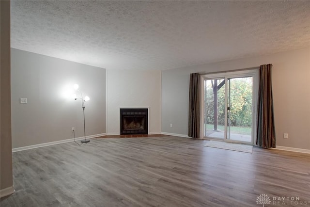 unfurnished living room with light wood-type flooring and a textured ceiling