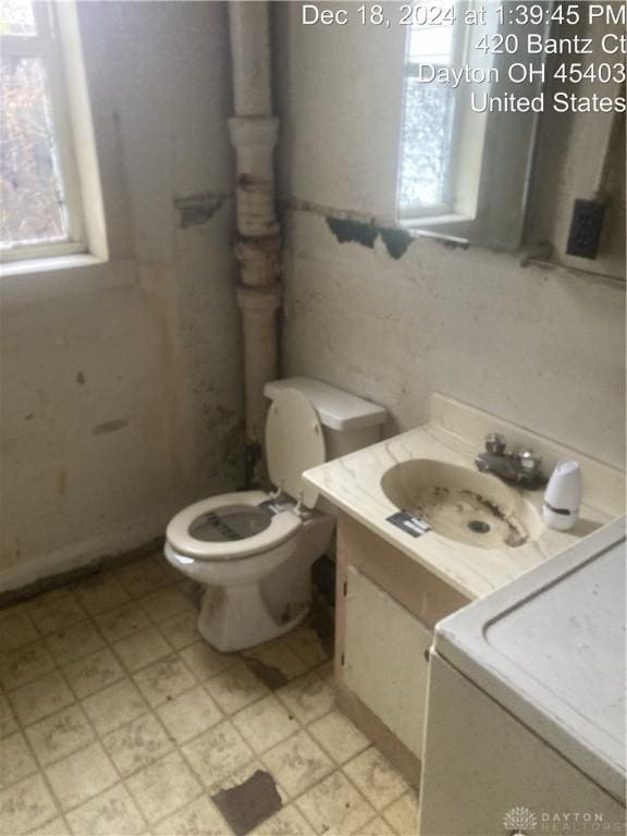 bathroom featuring vanity, toilet, and washer / clothes dryer