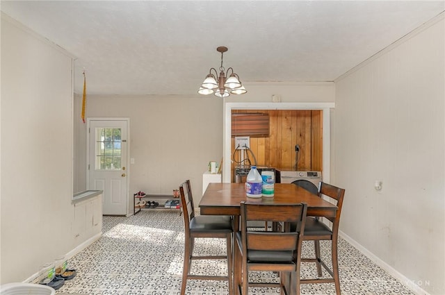 dining area with washer / clothes dryer, ornamental molding, and an inviting chandelier