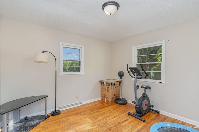 exercise room featuring a textured ceiling and light hardwood / wood-style flooring