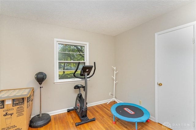 exercise area with hardwood / wood-style floors and a textured ceiling