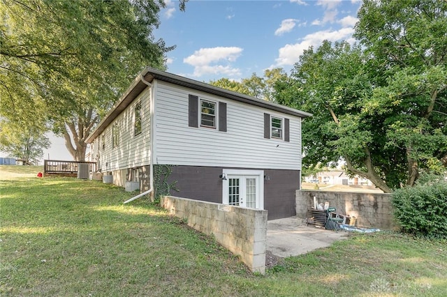 view of property exterior featuring french doors, a patio, a deck, and a lawn