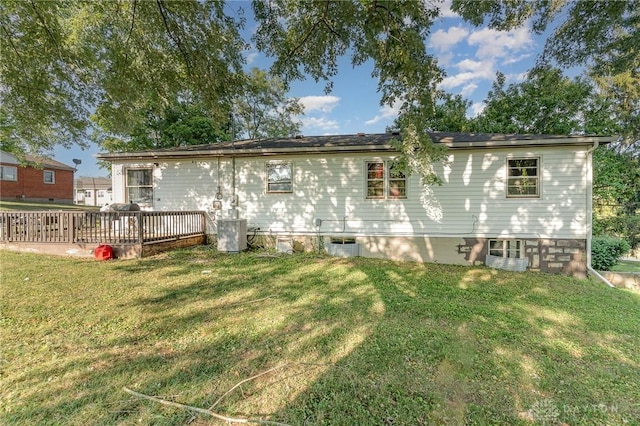 rear view of property with a lawn, central air condition unit, and a wooden deck