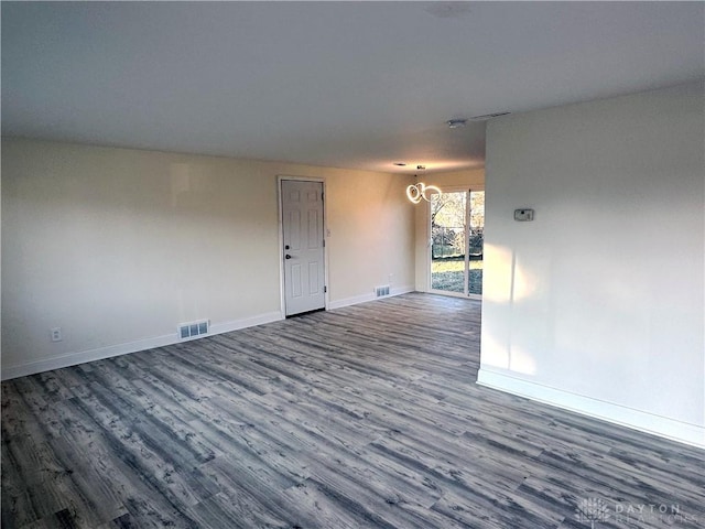 empty room featuring hardwood / wood-style floors and an inviting chandelier