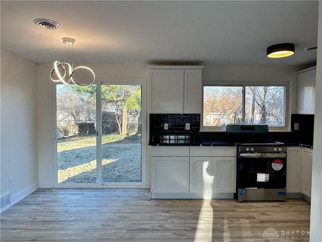 kitchen featuring stainless steel electric range, plenty of natural light, white cabinets, and decorative light fixtures