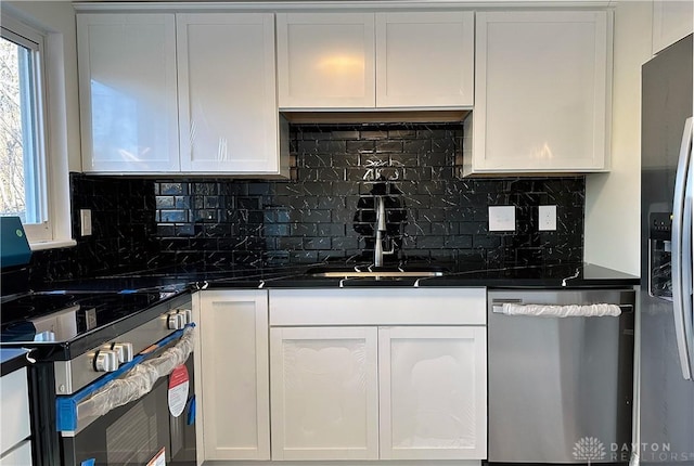 kitchen featuring appliances with stainless steel finishes, backsplash, white cabinetry, and sink