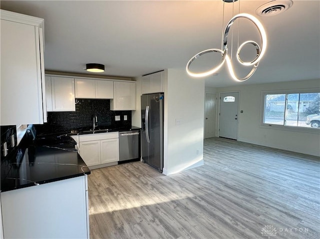 kitchen with white cabinets, sink, hanging light fixtures, decorative backsplash, and appliances with stainless steel finishes