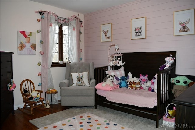 bedroom featuring dark wood-type flooring and wood walls