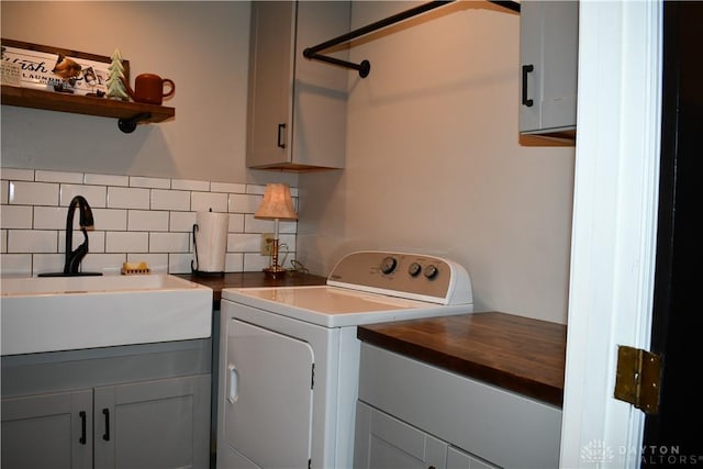 clothes washing area featuring washing machine and dryer, sink, and cabinets