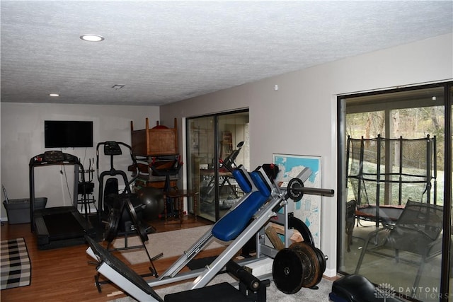 exercise area featuring wood-type flooring and a textured ceiling