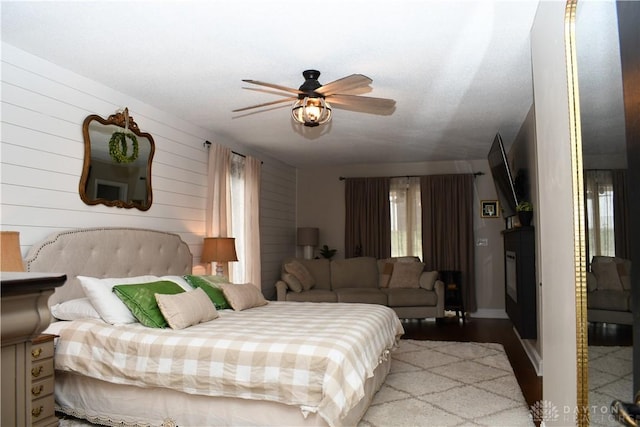 bedroom featuring ceiling fan and wooden walls