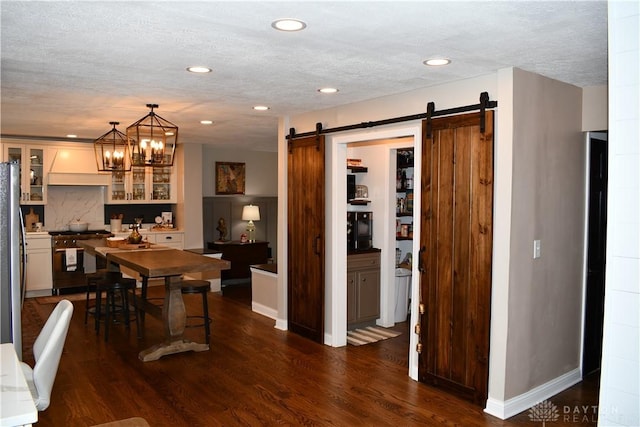 dining room featuring dark hardwood / wood-style flooring, a barn door, a textured ceiling, and an inviting chandelier