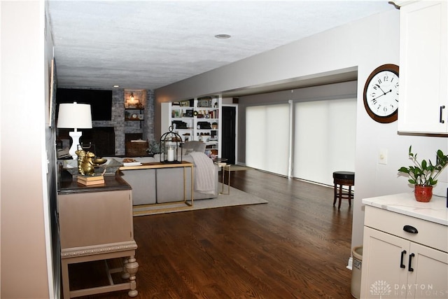 living room with built in shelves, a large fireplace, and dark hardwood / wood-style floors