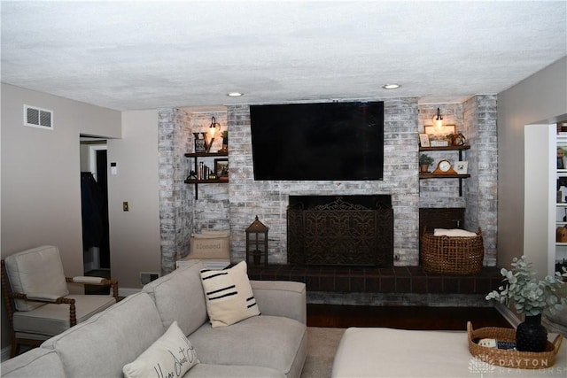 living room with built in shelves, a textured ceiling, and a brick fireplace