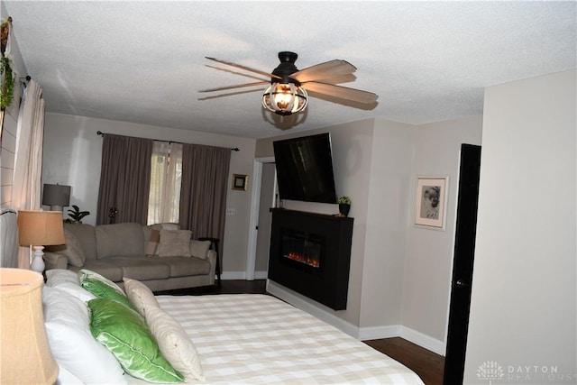 living room featuring ceiling fan, wood-type flooring, and a textured ceiling