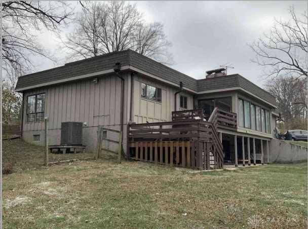 exterior space featuring a lawn, a sunroom, cooling unit, and a wooden deck