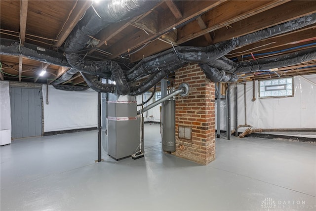 basement featuring water heater, gas water heater, and heating unit