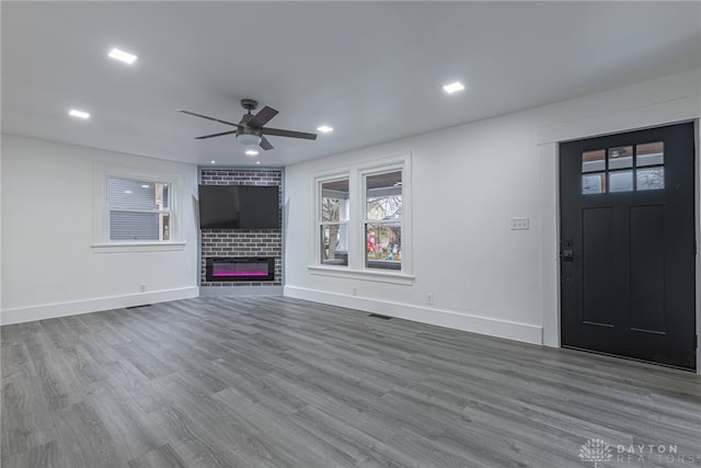 unfurnished living room featuring hardwood / wood-style floors, a brick fireplace, and ceiling fan