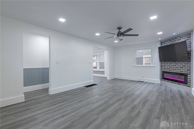 unfurnished living room featuring a fireplace, wood-type flooring, and ceiling fan