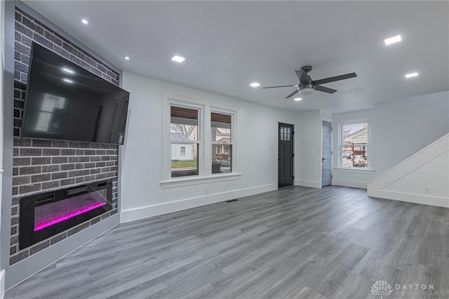 unfurnished living room with hardwood / wood-style floors, ceiling fan, a healthy amount of sunlight, and a fireplace