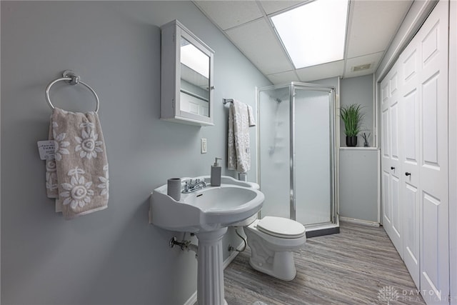 bathroom featuring hardwood / wood-style floors, a paneled ceiling, toilet, and a shower with shower door