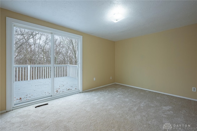 carpeted empty room featuring a textured ceiling