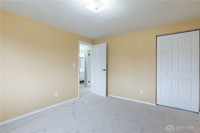 unfurnished bedroom with light colored carpet and a closet