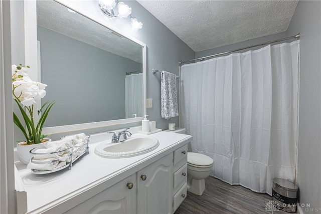 bathroom featuring walk in shower, vanity, a textured ceiling, hardwood / wood-style floors, and toilet