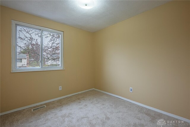 carpeted empty room featuring a textured ceiling