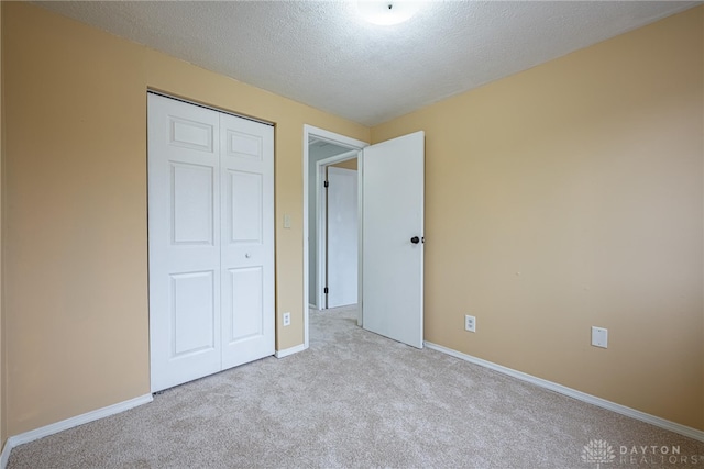 unfurnished bedroom with a textured ceiling, light colored carpet, and a closet