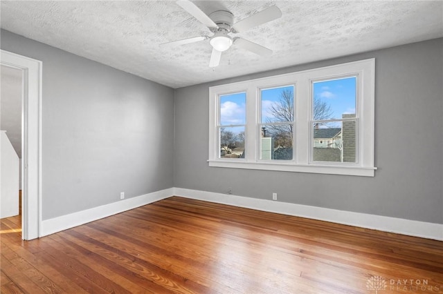 empty room featuring hardwood / wood-style flooring, ceiling fan, and a textured ceiling