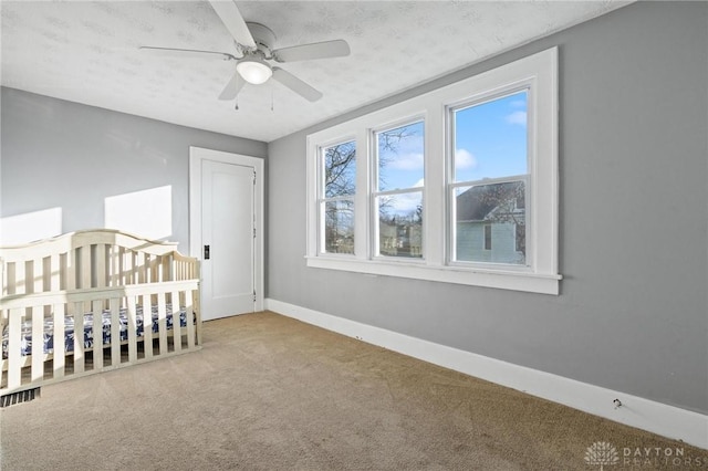 unfurnished bedroom featuring ceiling fan, light colored carpet, and a textured ceiling