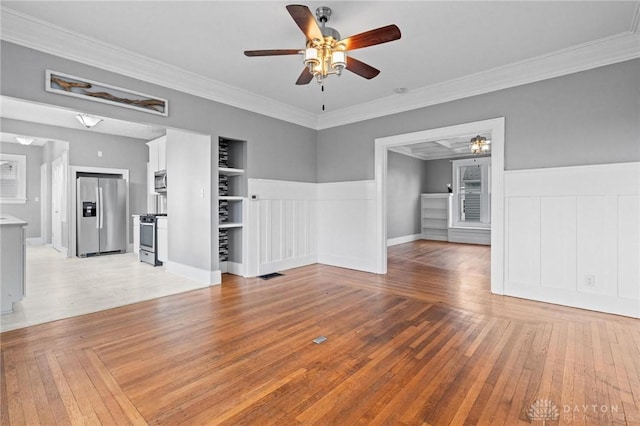 unfurnished living room featuring ceiling fan, built in features, light hardwood / wood-style flooring, and ornamental molding