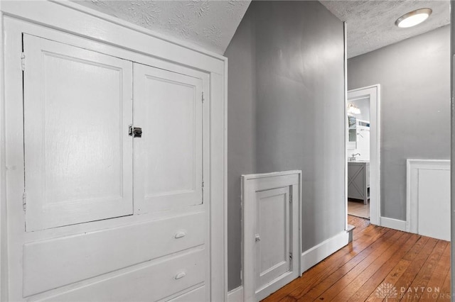 hall with hardwood / wood-style floors and a textured ceiling