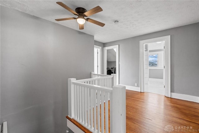 corridor with a textured ceiling and hardwood / wood-style flooring