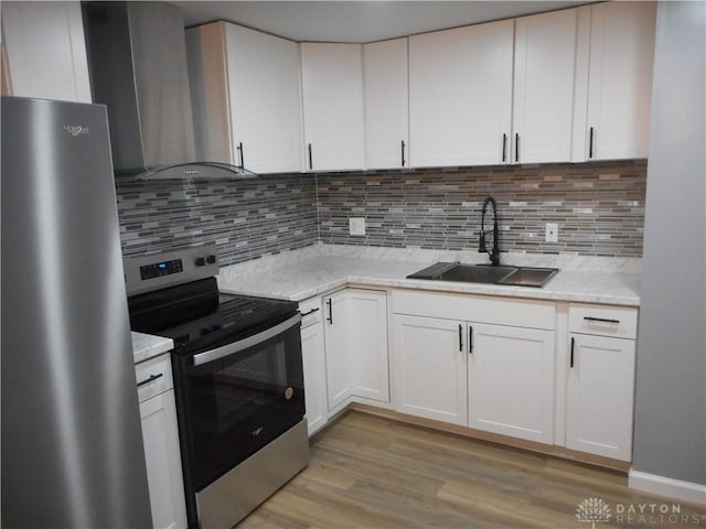 kitchen featuring white cabinetry, sink, stainless steel appliances, wall chimney range hood, and tasteful backsplash