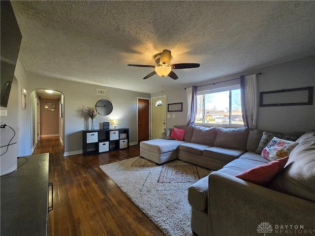 living room featuring a textured ceiling, ceiling fan, and dark wood-type flooring