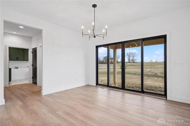 unfurnished dining area featuring recessed lighting, a notable chandelier, a wealth of natural light, and light wood-type flooring