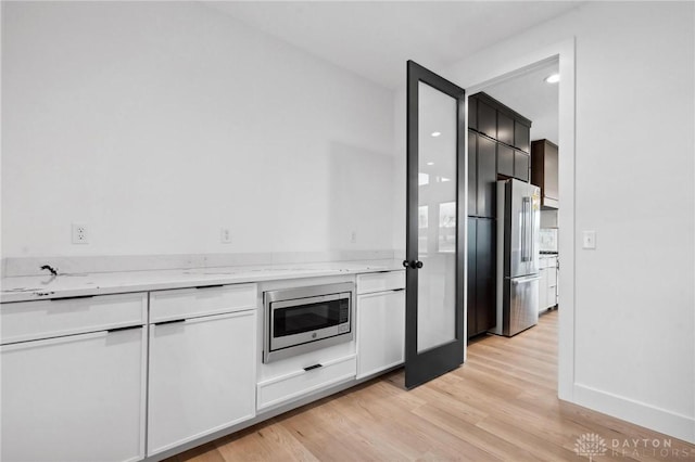 kitchen with light wood-style floors, light stone counters, and stainless steel appliances