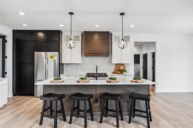 kitchen with light countertops, decorative backsplash, stainless steel fridge, and white cabinetry